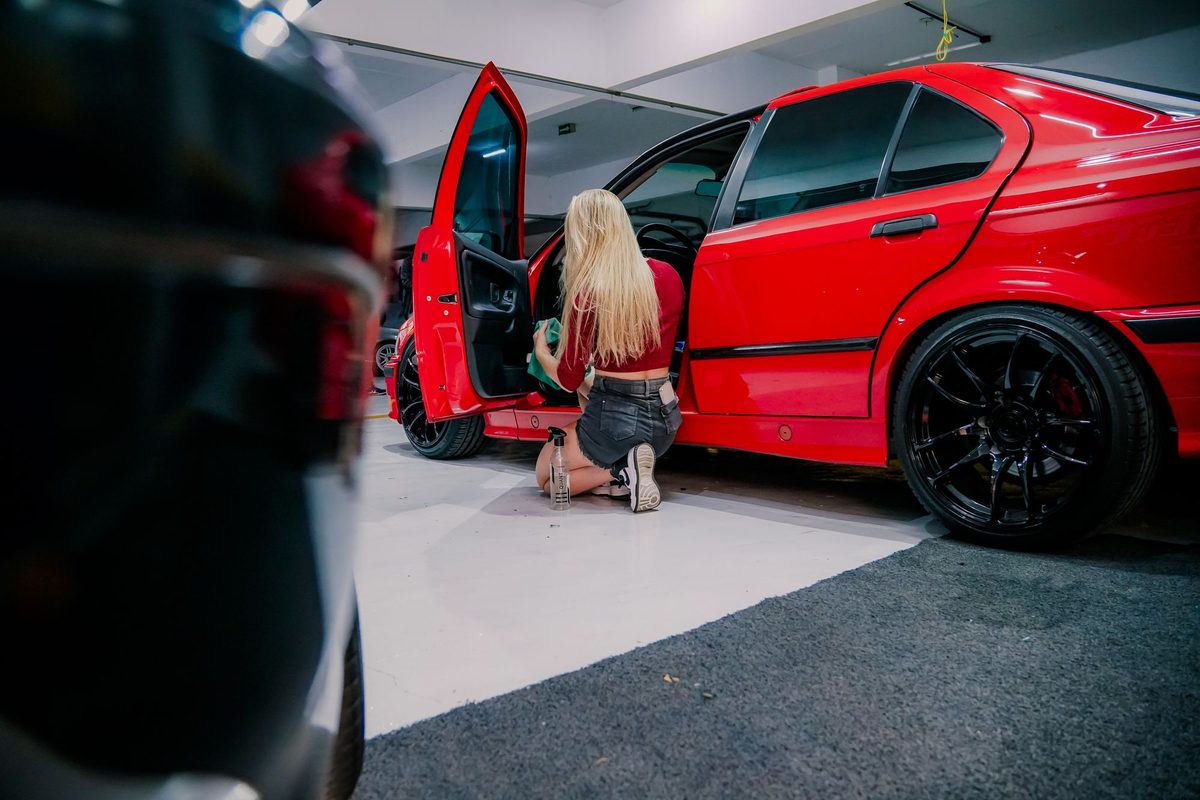 Detailer cleaning a car interior through the open door