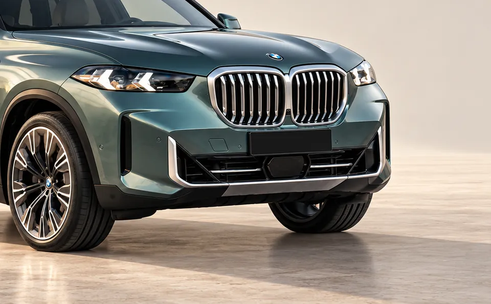 The front wheel, headlight and grille of a freshly detailed green BMW X5 in soft studio light
